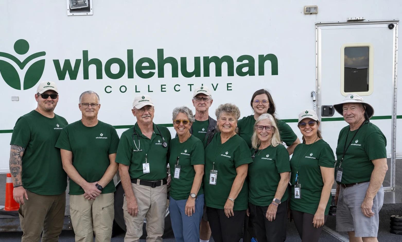 Members of the Wholehuman Collective team in green Wholehuman shirts standing in front of a vehicle with the Wholehuman Collective logo